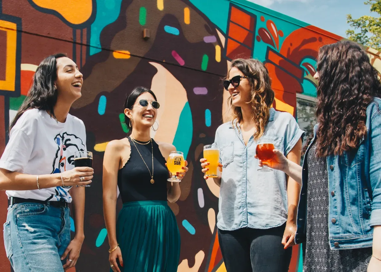 Roomies conviviendo felices frente a un mural colorido en la CDMX — la experiencia comunitaria de Roomies Express